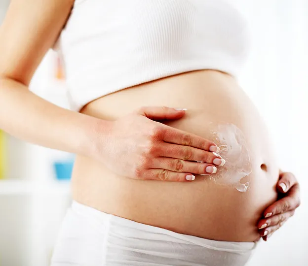 femme enceinte qui se masse le ventre avec de la creme à Mas-Grenier dans le Tarn-et-Garonne 82